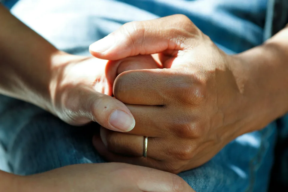 Two people holding hands in a supportive and respectful gesture